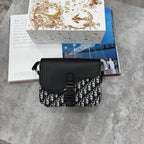 Black handbag with patterned design on a gray surface with books in the background